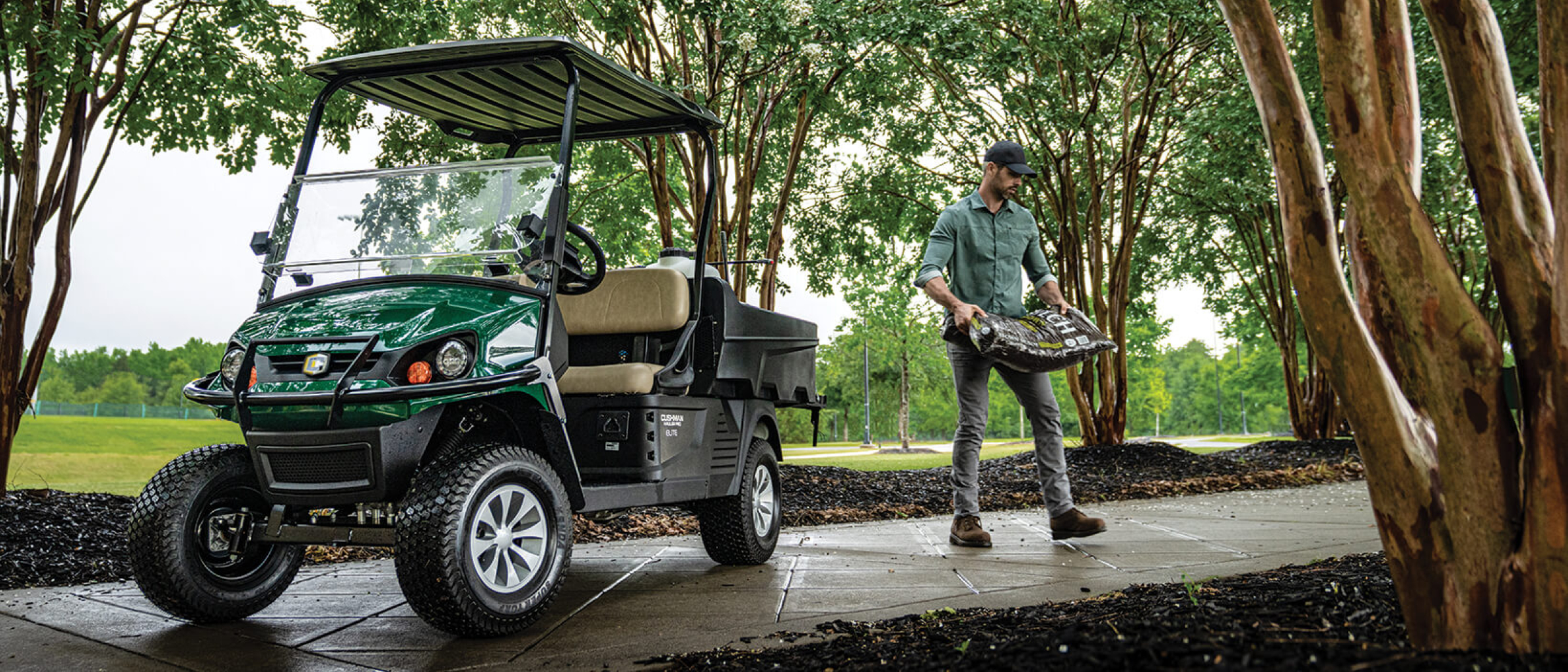 Cushman Hauler Pro ELiTE with a guy taking mulch from bed of Hauler to ground
